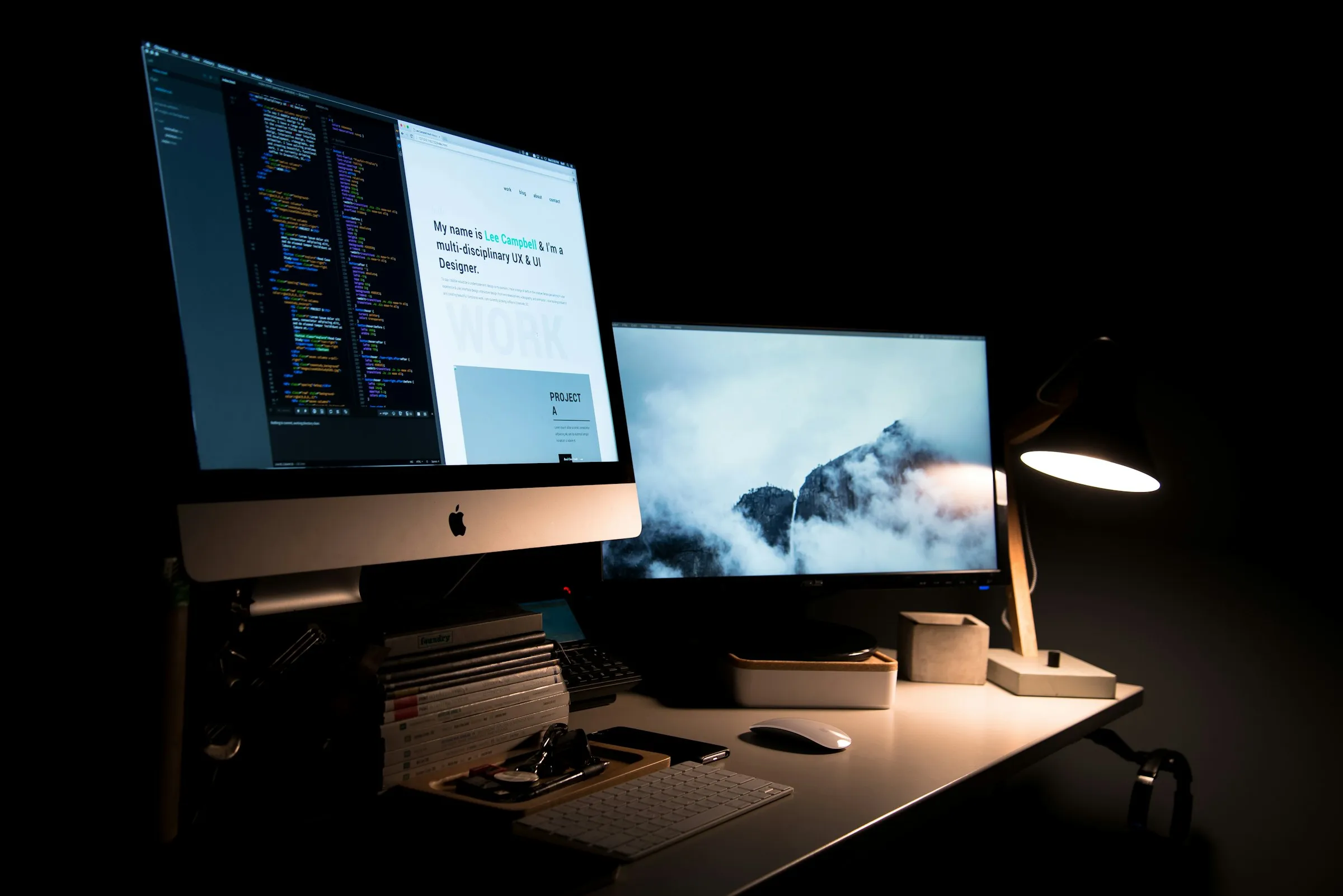 Monitores con código sobre un escritorio iluminado por una lámpara